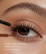 Close-up of a person's eye applying the Plume Elite Prostaglandin-Free Lash & Brow Enhancing Serum. Showing fuller-looking lashes and brows. Text at the bottom reads 'Visibly fuller-looking lashes & brows in as little as 17 days'.